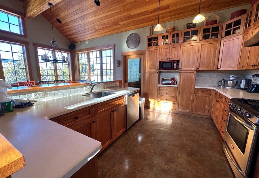 Spacious kitchen with natural wood cabinetry and stainless steel appliances in a mountain vacation rental home, showcasing a well-maintained interior as part of summer maintenance for vacation rentals.